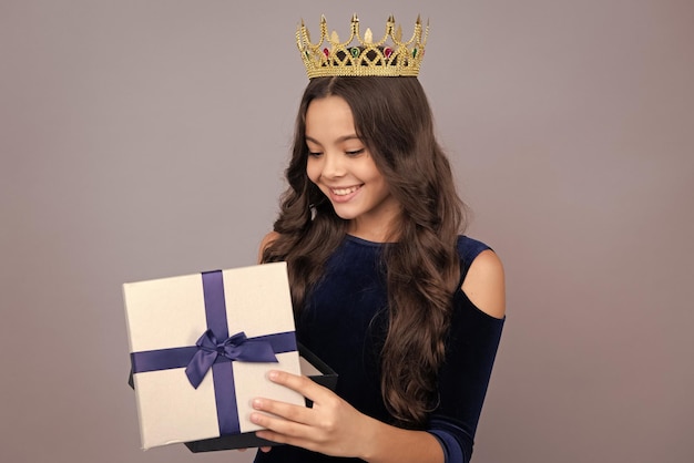 Niño con caja de regalos en fondo aislado Regalos para cumpleaños Día de San Valentín Año Nuevo o Navidad Rostro feliz de la princesa en corona emociones positivas y sonrientes de una adolescente