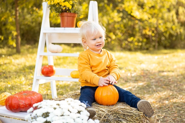 Niño con calabazas en el fondo del parque de otoño