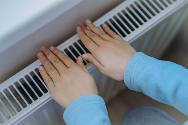 Foto niño calentándose las manos sobre el calentador crisis energética en europa