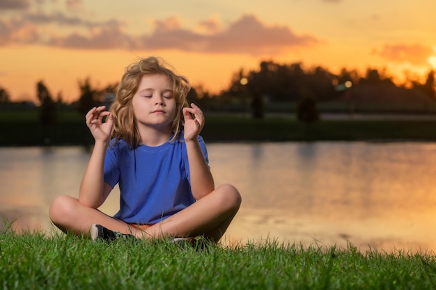 Niño calma y relajarse en el fondo de la naturaleza niño pequeño medita mientras practica yoga libertad y c