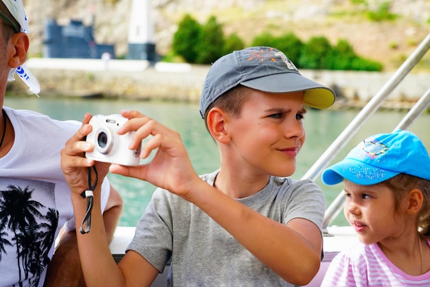 Un niño con una cámara en un barco de recreo en el mar.