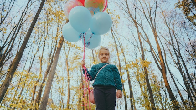 Un niño camina en el bosque con un montón de bolas de colores Niña con globos de colores en la mano