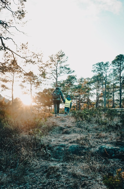 Un niño camina en el bosque con el sol detrás de él.