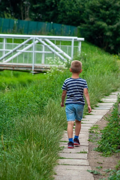 el niño camina por el camino a lo largo del arroyo