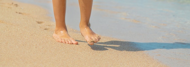 El niño camina por la playa dejando huellas en la arena.