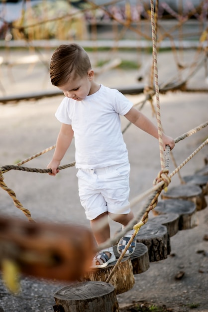 Un niño camina por un puente de madera estirado en una ciudad de cuerda