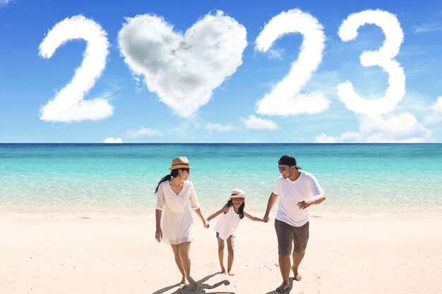 Niño camina con sus padres en la playa con números 2023