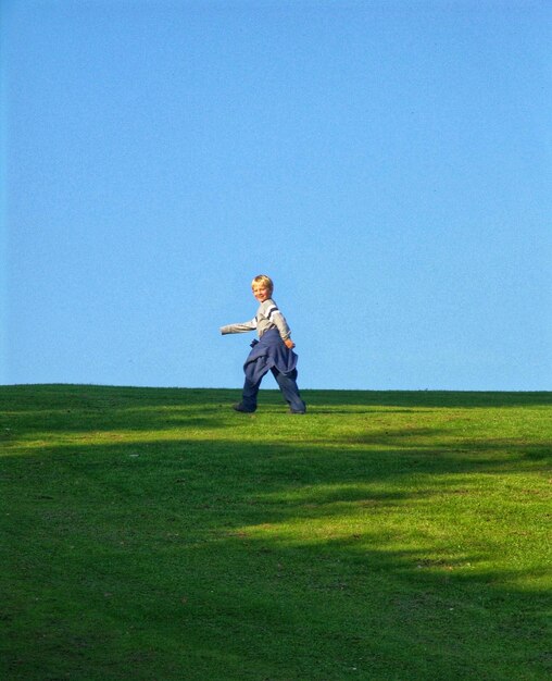 Foto niño caminando por el campo contra un cielo despejado