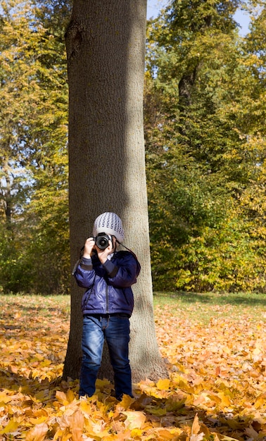 Foto un niño caminando en el parque que toma fotografías de su entorno.