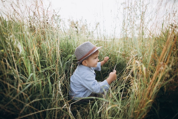 Niño caminando en una pradera con hierba alta en puesta de sol