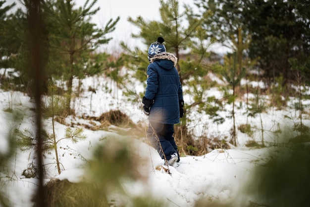 Niño caminando solo en el bosque de invierno