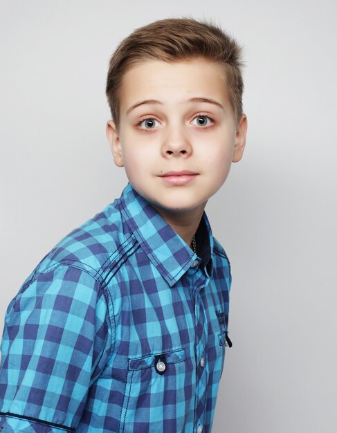 Niño con camisa azul sobre fondo gris