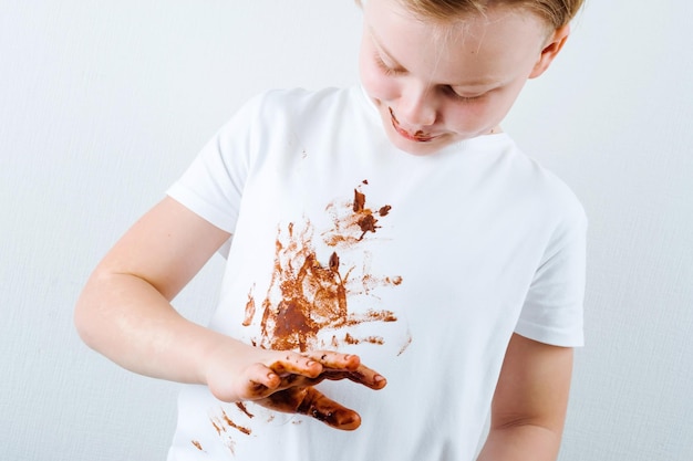 Un niño con una camisa blanca con chocolate