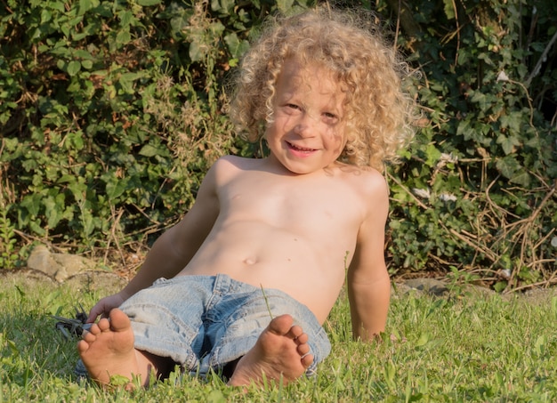 Niño sin camisa jugando en el jardín