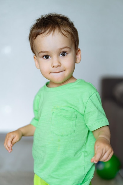 Niño con camisa y pantalones verdes Un niño vestido con camisa y pantalones verdes posa para la cámara