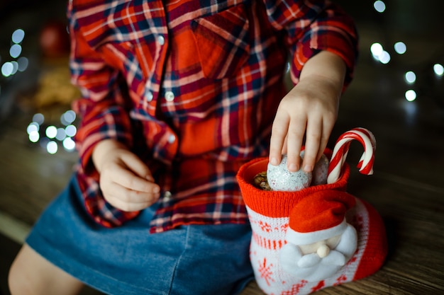 Un niño en una camisa roja a cuadros toma dulces de un dulce regalo de Navidad