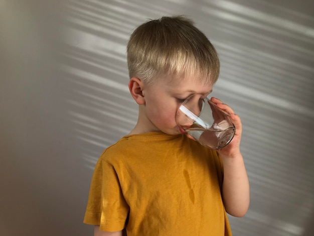 un niño con una camiseta amarilla bebe agua