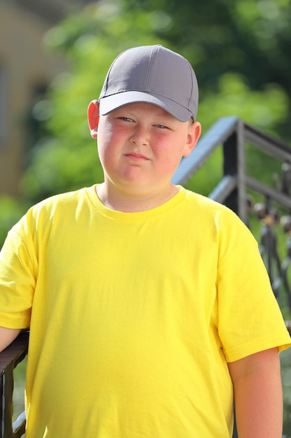 Un niño con una camiseta amarilla, una gorra y gafas de sol se encuentra en la naturaleza. Foto de alta calidad