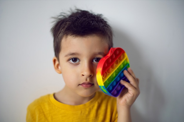 Un niño con una camiseta amarilla juega un juego de moda revienta en forma de manzana de silicona