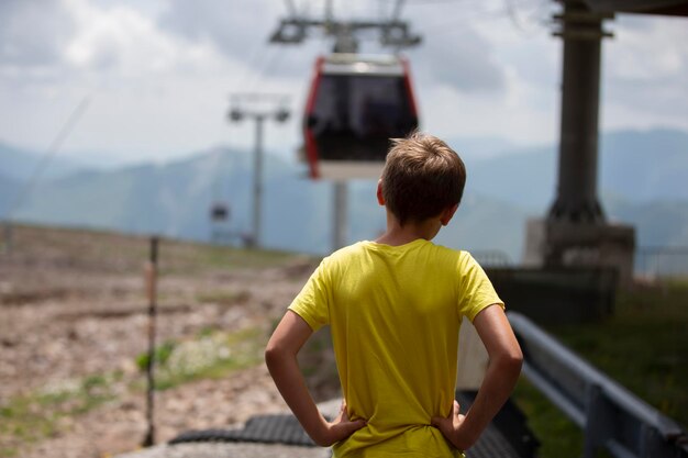 Un niño con una camiseta amarilla mira el teleférico.