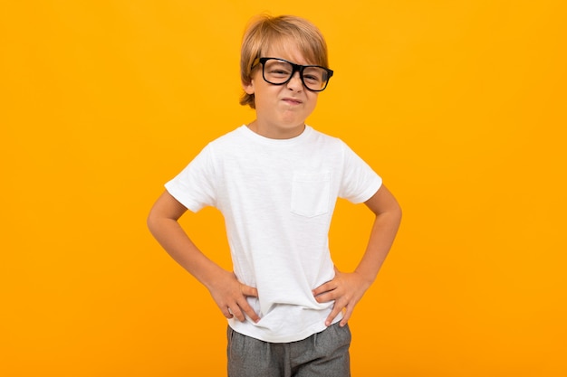 Niño con una camiseta blanca entrecerrando los ojos en gafas de color amarillo con espacio de copia