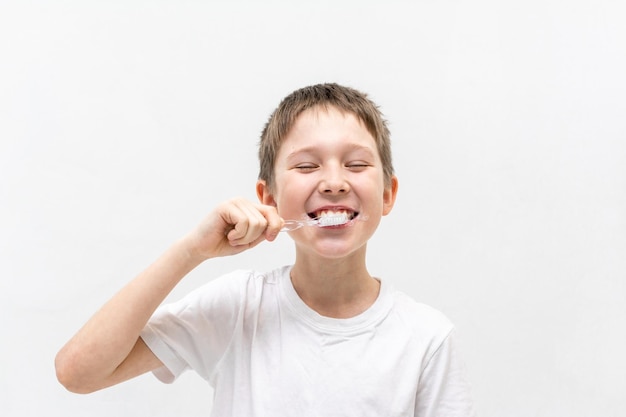 Un niño con una camiseta blanca se está cepillando los dientes en el baño