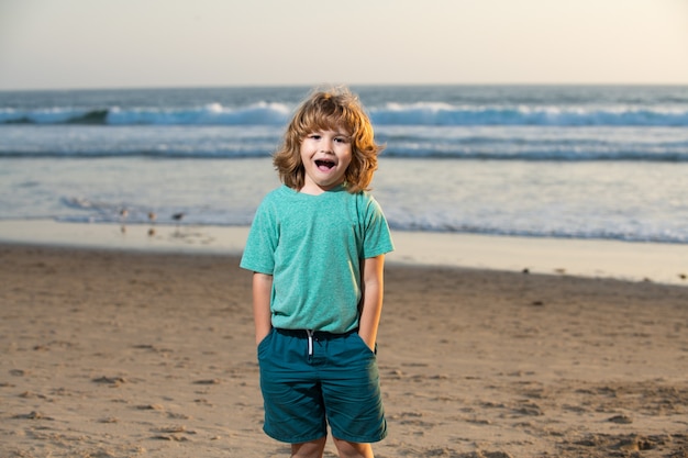 Niño en camiseta caminando por la playa de verano. Emociones de niños sorprendidos asombrados.