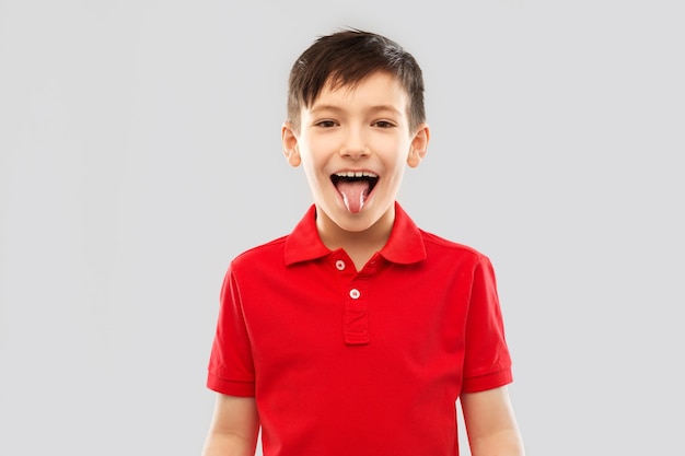 niño con camiseta de polo roja mostrando su lengua