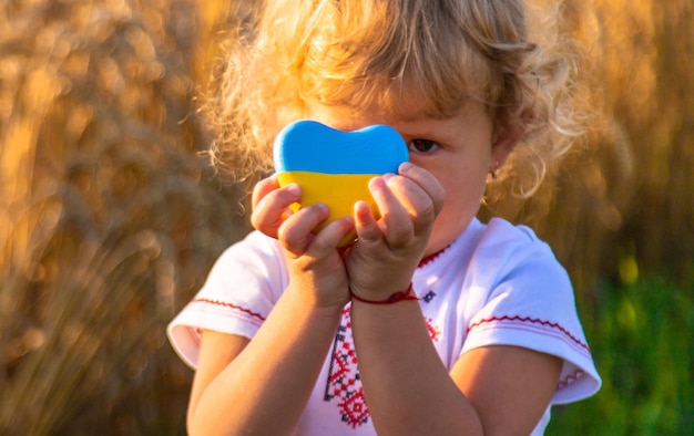 Niño en un campo de trigo con la bandera de Ucrania Enfoque selectivo Naturaleza