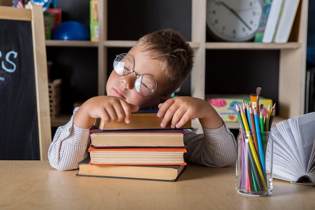 Foto niño cansado durmiendo en una pila de libros