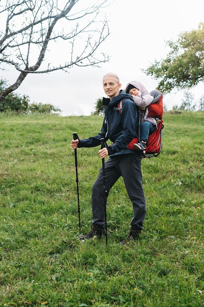 Niño cansado soñoliento caminando con el padre en la mochila al aire libre