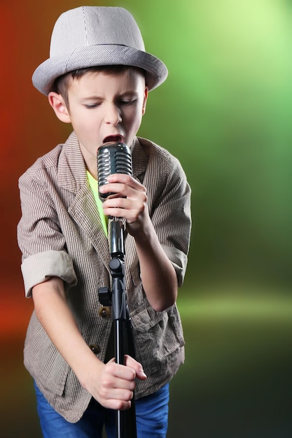 Foto niño cantando con micrófono sobre un fondo brillante