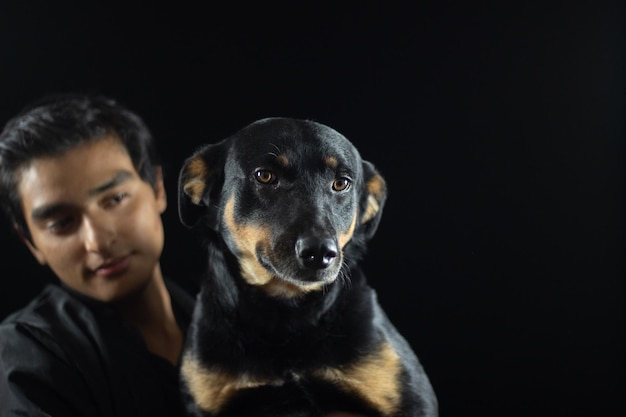 Niño cargando a su perro, ambos posando para la foto, el perro tiene una cara tierna y alegre, siente el amor de su humano y se lo pasa bien.