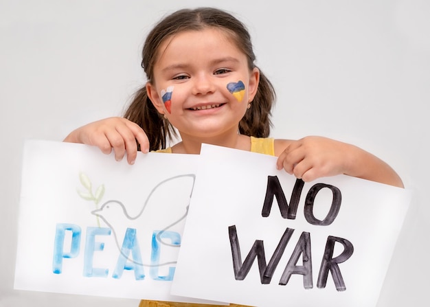 Niño con carteles sin guerra y paz en un fondo gris