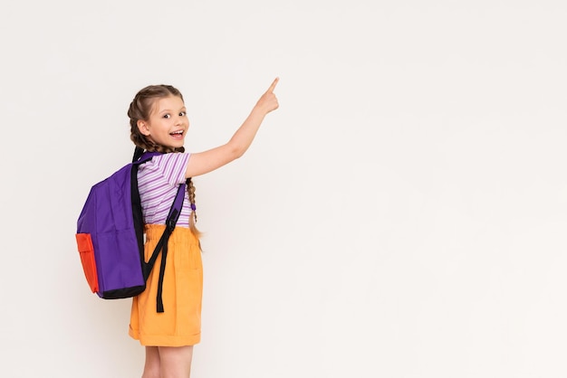 Un niño con una cartera apunta con su dedo índice a su anuncio