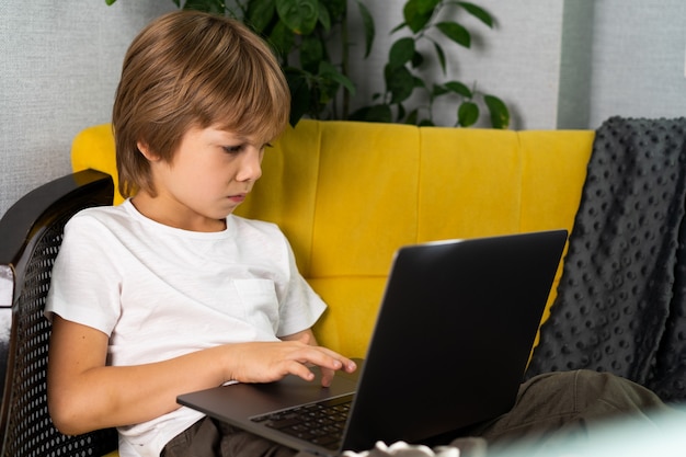 Niño en casa con laptop aprendiendo en línea