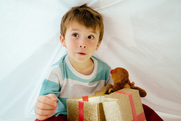 Niño en casa en la mañana de Navidad con regalo