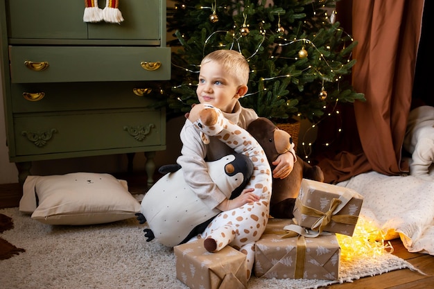 Niño en casa de Navidad cerca de guirnaldas festivas cerca de lindos juguetes