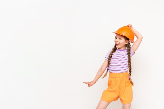 Un niño con un casco de construcción señala su anuncio Una niña con coletas sobre un fondo blanco aislado Profesión en la industria de la construcción