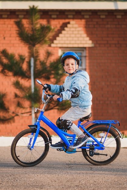 Niño en casco monta una bicicleta en un día soleado