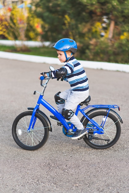 Un niño con un casco y protección en un paseo en bicicleta por la naturaleza en la primavera.