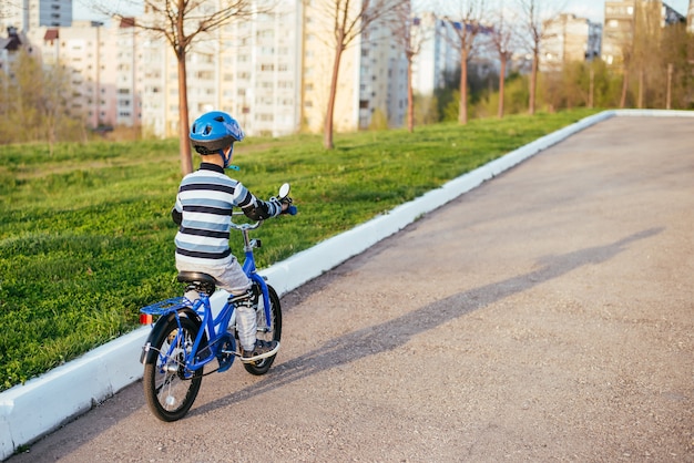 Un niño con un casco y protección en un paseo en bicicleta por la naturaleza en la primavera.