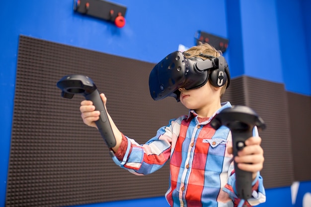 Niño con casco de realidad virtual jugando videojuegos en el centro de juegos