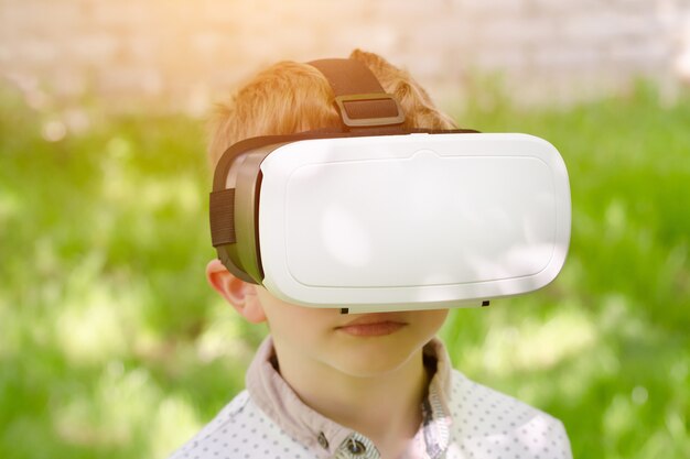 Niño en un casco de realidad virtual sobre un fondo de hierba verde