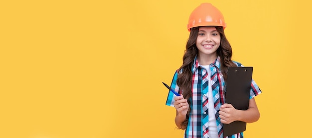 Niño con casco sostiene los documentos de construcción del proyecto firmando un contrato niño constructor con casco