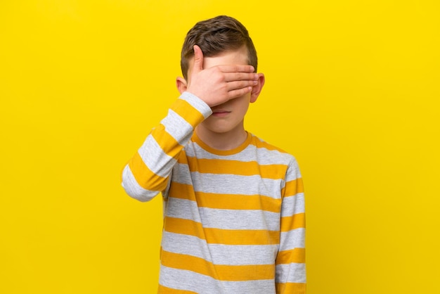 Un niño caucásico aislado de fondo amarillo cubriendo los ojos con las manos No quiero ver algo