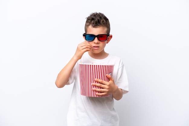 Niño caucásico aislado de fondo blanco con gafas 3d y sosteniendo un gran cubo de palomitas de maíz