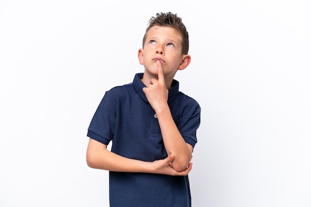 Foto un niño caucásico aislado de fondo blanco que tiene dudas mientras mira hacia arriba