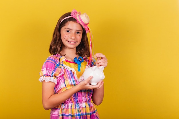 Niño caucásico brasileño Festa Junina ropa foto de primer plano finanzas con hucha dinero ahorro moneda mayo junio y julio festividades festa junina celebraciones