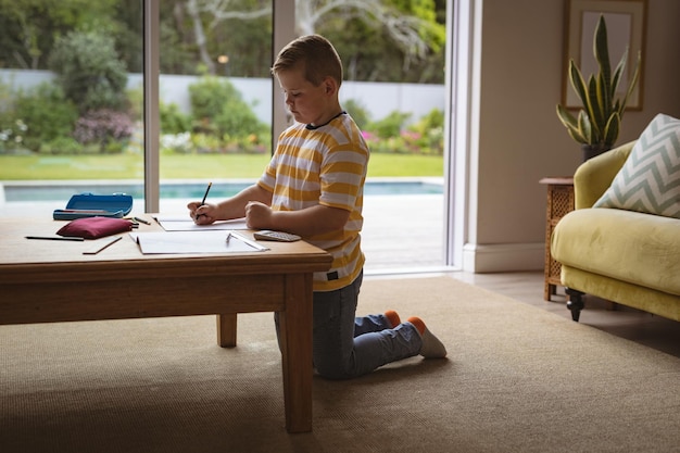 Foto niño caucásico dibujando en su libro sentado en la sala de estar en casa